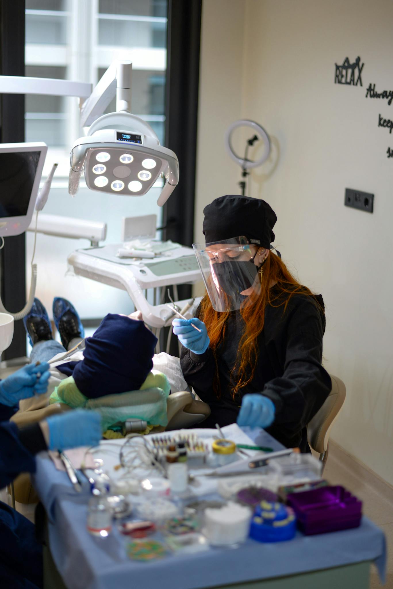 A female dentist in protective gear working on a patient in a dental clinic setting.